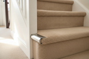 Silver anodised aluminium stair nosing end cap fitted to a carpeted staircase edge in a UK home hallway