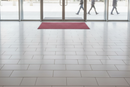 Red mix heavy duty entrance barrier mat laid just inside a retail shop entrance on polished floor tiles