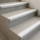 Tile-in stair nosings with white anti-slip inserts set flush into grey tiled steps