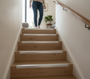 Aluminium anti-slip step nosing installed on laminate UK home staircase - woman walking up, surface mount screw fix