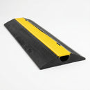 Single channel black rubber floor cable cover with yellow top strip and sloped edges, one cable channel visible at the cut end