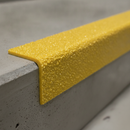Close-up of impregnated quartz grit surface on yellow GRP stair nosing 55x55mm — BS7976.2 certified