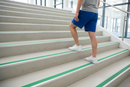 Anti-slip aluminium stair nosing with Green PVC insert — installed on UK staircase with person using the stairs
