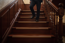 uPVC wood effect stair nosing in Mahogany — real-life installation on UK staircase with person using the stairs