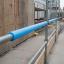 Blue foam pipe protector fitted over a low-level scaffold guardrail pole at a pedestrian walkway on a construction site