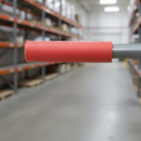 Red foam pipe protector fitted over an exposed steel pipe at head height inside a warehouse aisle