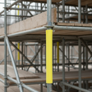 Yellow foam scaffold pole protector fitted over a scaffold tube at head height on a construction site