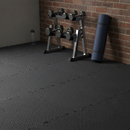 Black diamond-plate interlocking EVA foam floor tiles fitted in a home gym corner with a dumbbell rack and rolled yoga mat