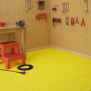 Yellow diamond-plate interlocking EVA foam floor tiles fitted in a home workshop corner with a pegboard tool wall
