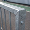Close-up of the welded mitred corner of a galvanised pedestrian guardrail, showing the 50 x 30mm rectangular hollow section top rail, zinc spangle finish, welded infill bar sockets and a galvanised panel connection bolt