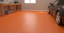 Orange interlocking PVC garage floor tiles fitted in a garage with black sports car