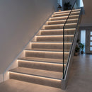 Genesis NLD LED tile-in stair nosing lighting the risers of a porcelain-tiled staircase in a modern hallway