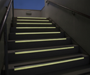 External fire escape staircase at dusk with glow-in-the-dark stair nosings lighting each step edge