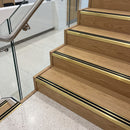 Gold anodised aluminium stair nosing with rubber inserts fitted full width on oak steps in an office stairwell