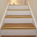 Gold anodised push-in LVT stair nosing 28x14.5mm fitted on warm oak vinyl treads in a lamp-lit hallway