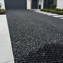 Black decorative gravel driveway with the underlying honeycomb ground reinforcement grid exposed at one corner
