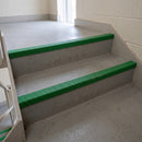 Green GRP anti-slip stair nosings fitted to the front edge of concrete steps in a stairwell
