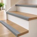 Grey self-adhesive PVC stair nosing 50x48mm fitted to every step of a light oak staircase in a bright UK hallway