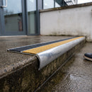 Bullnose aluminium stair nosing 98x40mm with twin Yellow / Black gritted GRP inserts, fitted to a concrete step at the external entrance to a commercial building