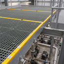 Grey GRP grating panels forming a raised maintenance platform above pumps in a UK plant room