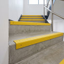 Yellow GRP stair nosings fitted to concrete steps in a commercial stairwell, wrapping each step edge