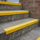Yellow GRP stair nosings on external concrete steps beside a brick wall