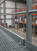 Grey GRP kick plate toe board fitted along the edge of a warehouse mezzanine platform guardrail