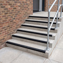 Black GRP anti-slip stair nosing fitted full width on concrete steps at a UK commercial entrance