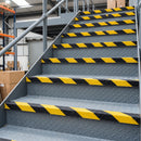 Black and yellow hazard stripe GRP stair nosing fitted full width on UK warehouse mezzanine steps