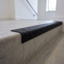Black GRP stair nosing fitted over a concrete step edge in an apartment block stairwell