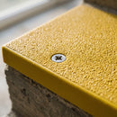Stainless steel countersunk screw set flush in the ceramic grit surface of a fitted GRP stair nosing