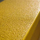 Close-up of the fine internal grade anti-slip grit on a yellow GRP stair nosing