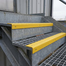 Yellow GRP stair nosings fixed over the open mesh treads of an external steel fire escape
