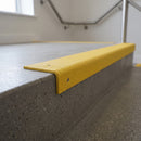 Yellow GRP stair nosing fitted over a concrete step edge in an office stairwell