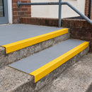 Dark grey GRP stair tread cover with yellow nosing fitted over external concrete entrance steps