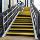 Black GRP anti-slip stair tread covers with yellow nosing fitted to an outdoor commercial staircase