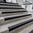 Black GRP anti-slip stair nosings fitted to concrete steps in a public building