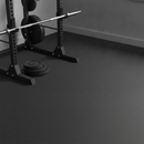 Home gym floor fully covered in plain black rubber gym flooring with a power rack and weight plates