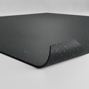 Black rubber gym flooring roll with blue flecks on studio background, corner rolled up to show thickness