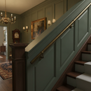 Antique brass wall-mounted stair handrail installed in a traditional period hallway staircase