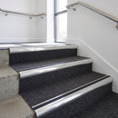 Heavy duty bullnose aluminium stair nosing with black insert in bright polished finish fitted on an office stairwell with charcoal contract carpet