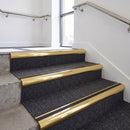Heavy duty bullnose aluminium stair nosing with black insert in mirrorflect gold finish fitted on an office stairwell with charcoal contract carpet