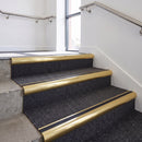 Heavy duty bullnose aluminium stair nosing with black insert in satin gold finish fitted on an office stairwell with charcoal contract carpet