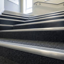 Grey insert carpet stair nosings on a dark charcoal carpeted office stairwell