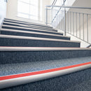 Red insert carpet stair nosings marking step edges on a blue grey carpeted school staircase