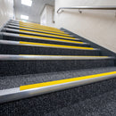 Yellow insert carpet stair nosings giving high contrast step edges on dark carpeted stairs