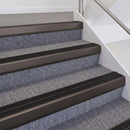 Dark bronze double insert chevron stair nosing with black inserts fitted on grey carpeted stairs