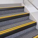 Satin black double insert chevron stair nosing with yellow inserts fitted on grey carpeted stairs