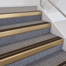 Satin bronze double insert chevron stair nosing with brown inserts fitted on grey carpeted stairs