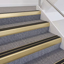 Satin gold double insert chevron stair nosing with black inserts fitted on grey carpeted stairs